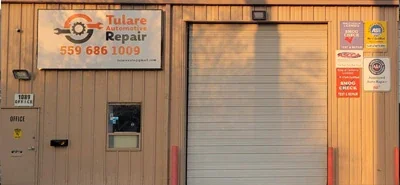 The front of the shop: the Tulare Automotive Repair sign with 559 686 1009 on it, beside the roll-up bay door and the office door.